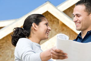 Couple looking at home plans in front of partial construction